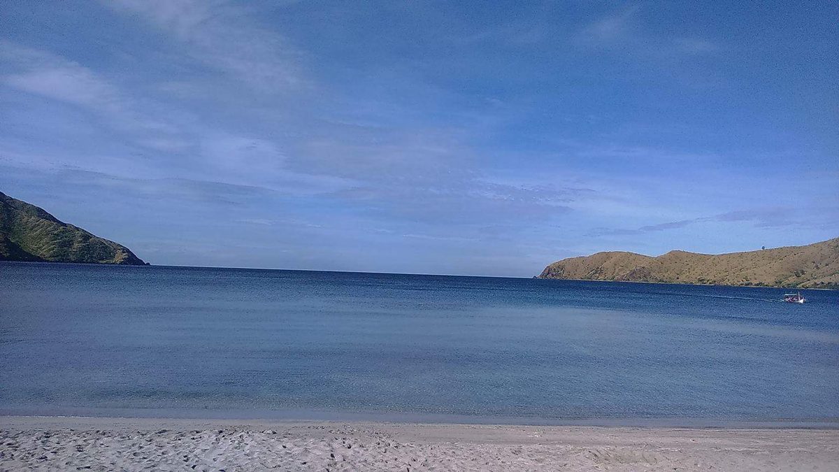 Nagsasa Cove in Zambales backed by green mountains, reached by boat from Pundaquit