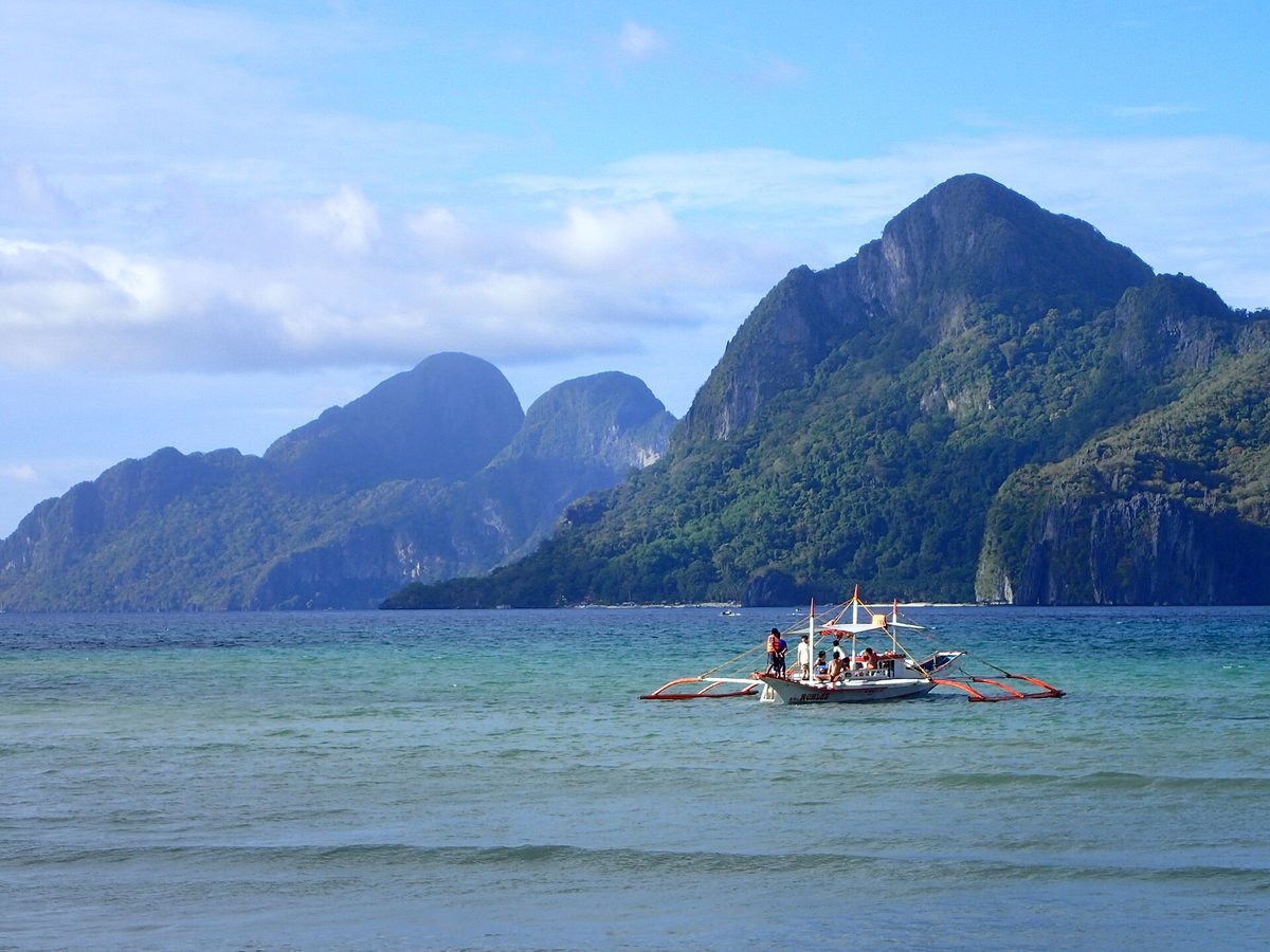 Beach near El Nido town with limestone cliffs across Bacuit Bay, Palawan, Philippines