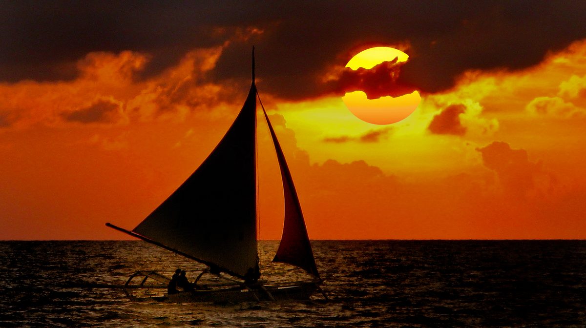 Traditional paraw sailboats off White Beach at sunset, Boracay Philippines