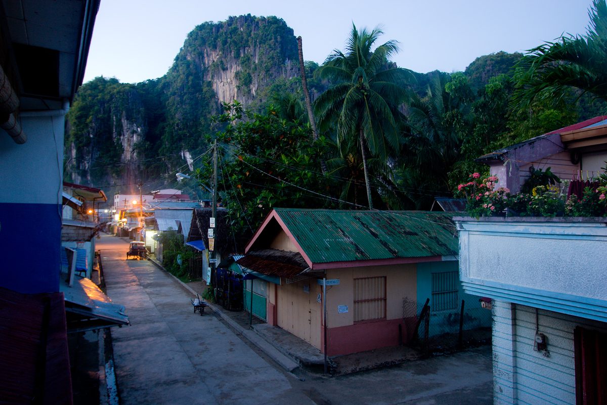 El Nido town beach backed by limestone cliffs and parked bangka boats