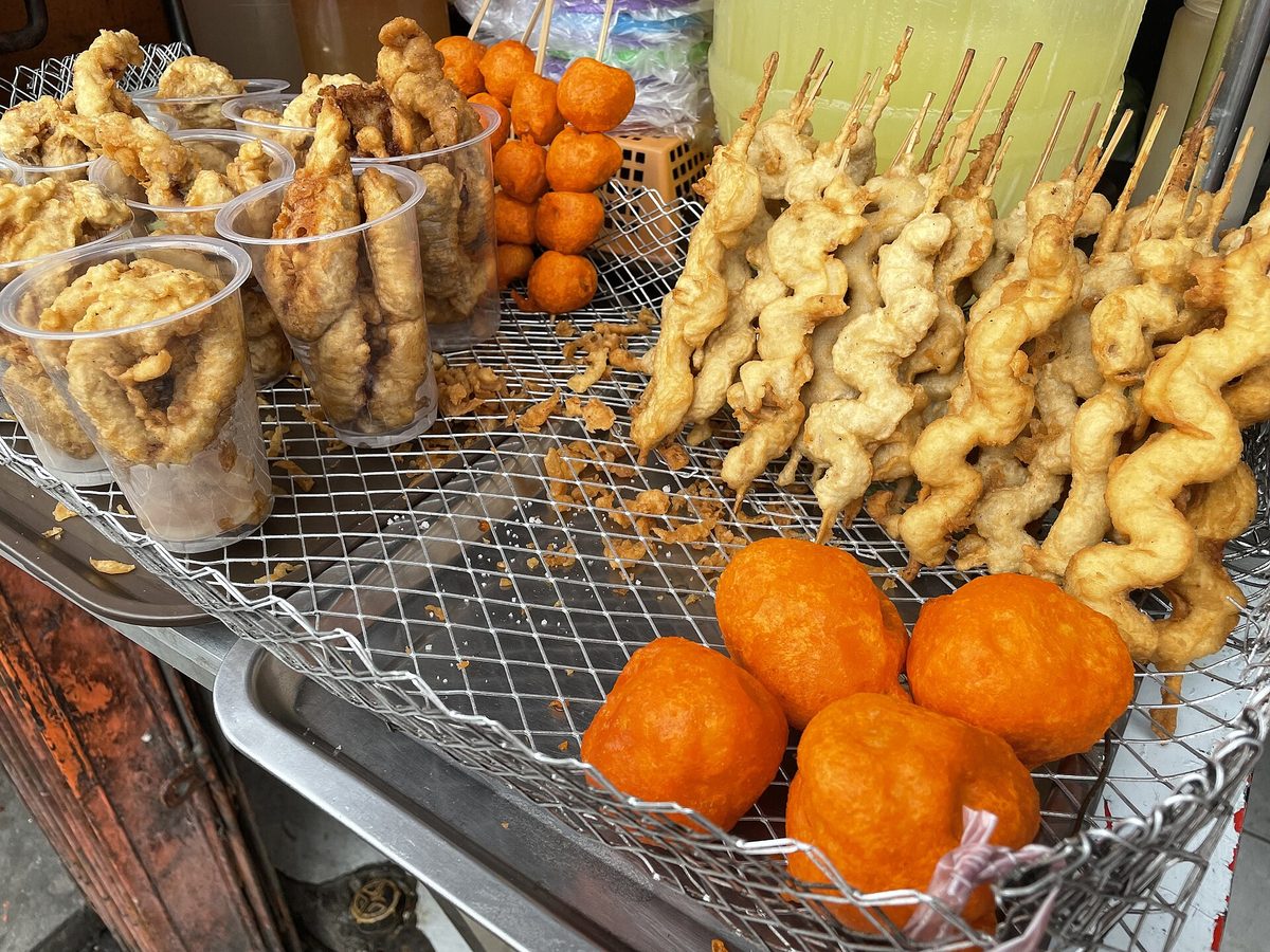 Filipino street-food skewers grilling over charcoal at a roadside stall