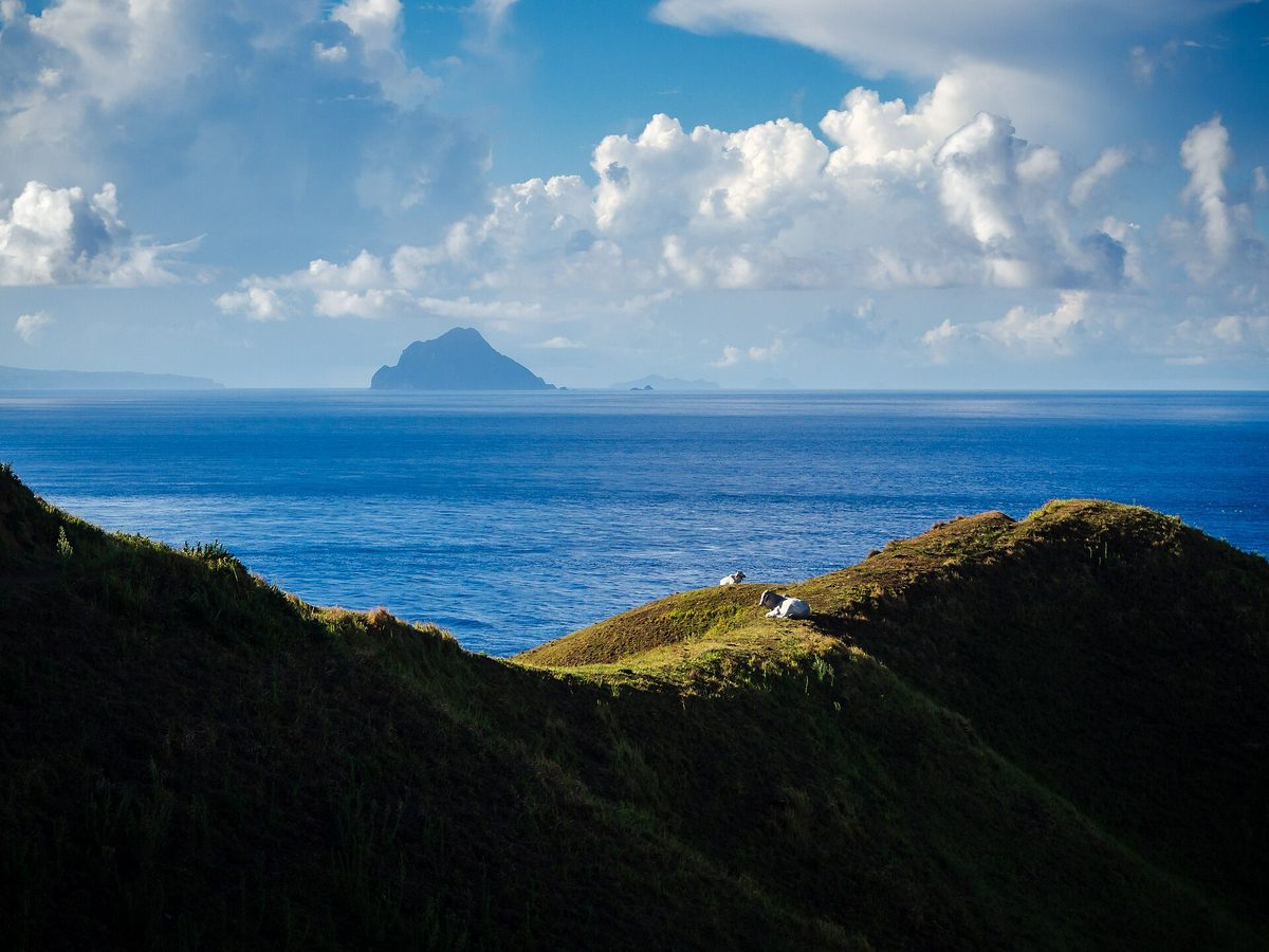 Rolling green hills meeting cliffs and the sea in Batanes, the most off the beaten path Philippines destination in the far north