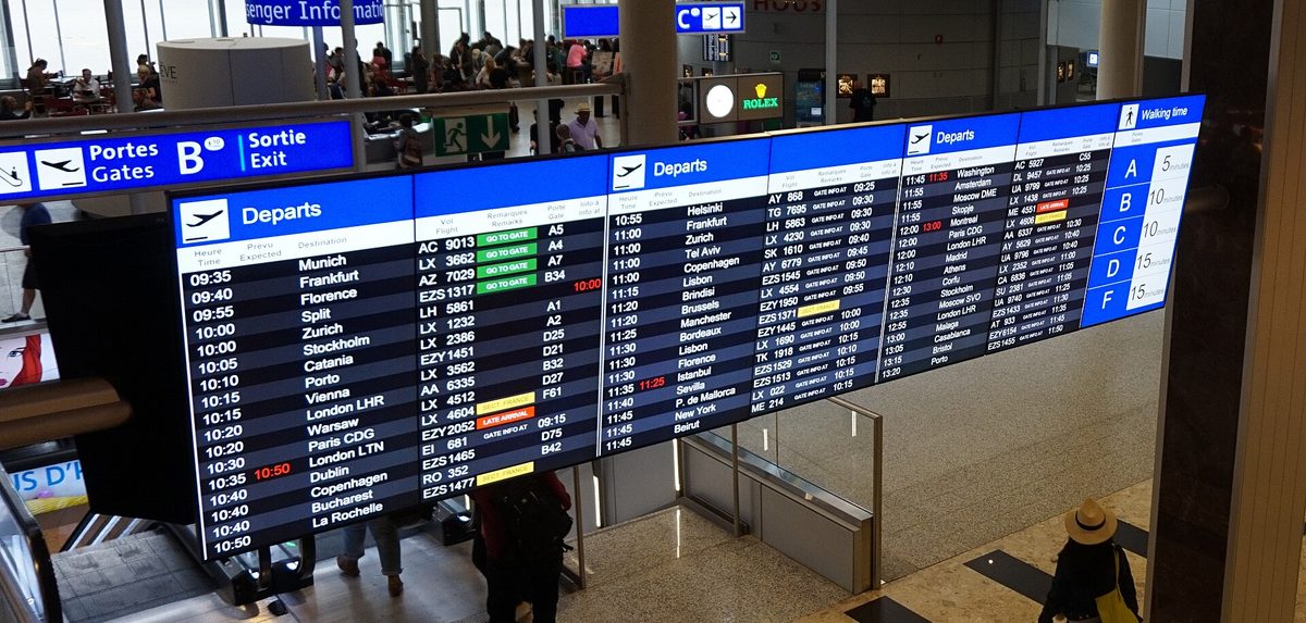 An airport departure board, a reminder to check missed-connection and travel-delay cover for storm-season flights