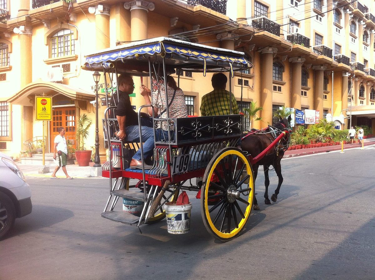 A kalesa horse-drawn carriage on a street in Manila, a traditional way to tour Intramuros
