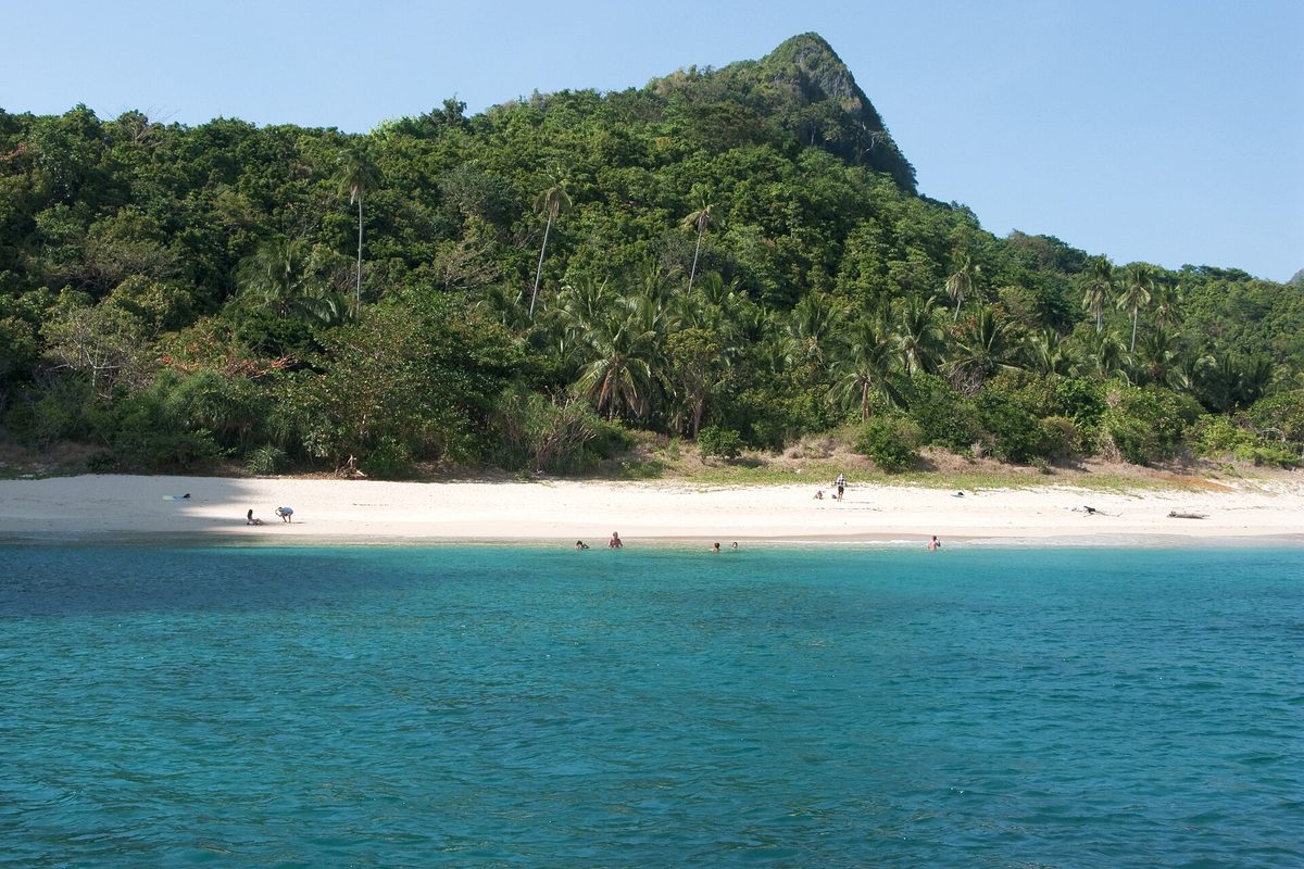 A white-sand beach backed by limestone karst on an island near El Nido in the Bacuit Archipelago, Palawan