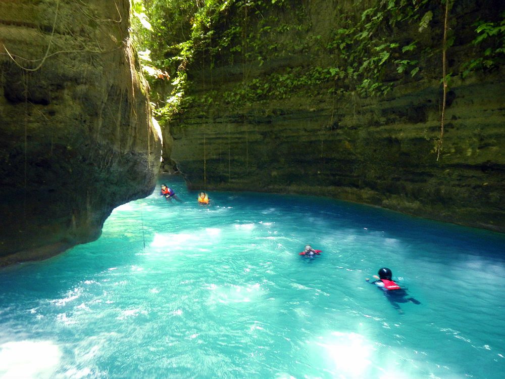 Visitors swimming in the blue basin at the foot of Kawasan Falls, Cebu