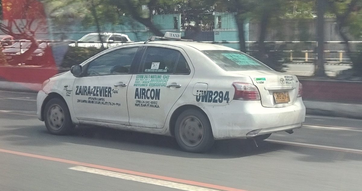 A white metered taxi in Manila, Philippines, where riders should insist on the meter