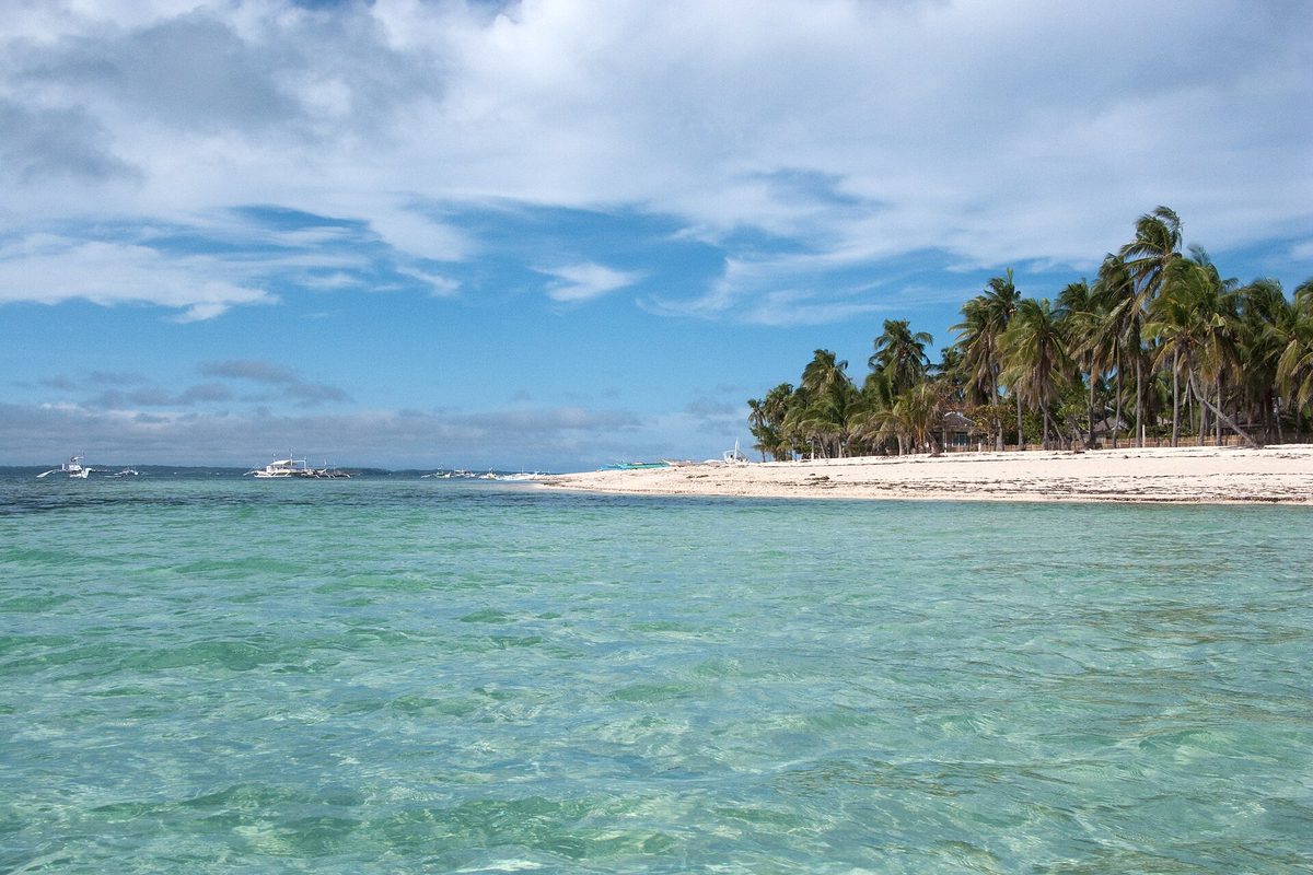 White-sand tropical beach fringed with palms on Malapascua Island, Cebu, Philippines