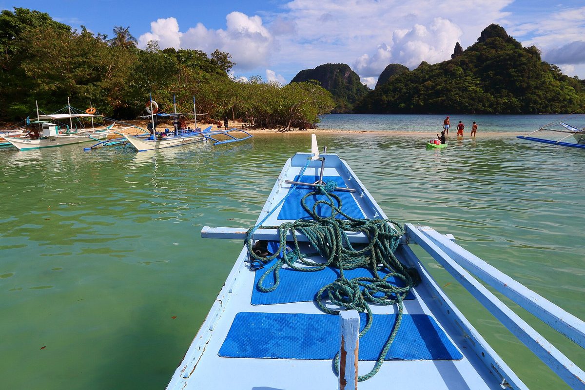 Traditional outrigger bangka boat anchored off a beach during island hopping in El Nido