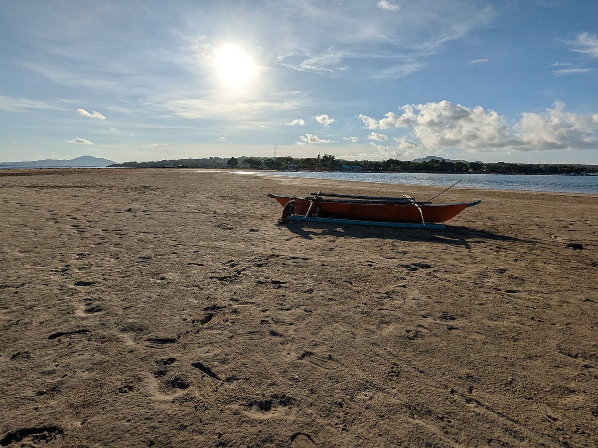 Traditional bangka outrigger boats moored off a white-sand beach in Palawan