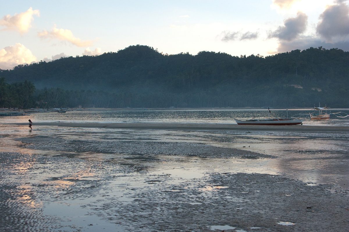 Sandy beachfront and outrigger boats at Port Barton in San Vicente, Palawan, Philippines