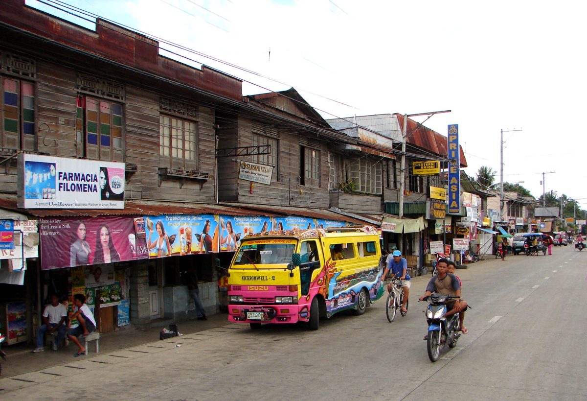 A motorcycle on the main street of Loon, Bohol, Philippines, with the countryside beyond