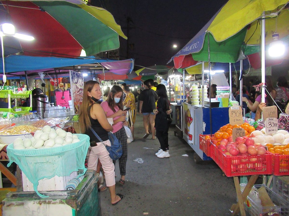 A busy Philippine night market with food stalls, where foreigner price markups and pickpocketing happen