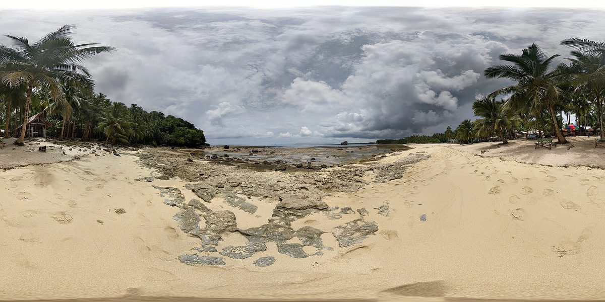 The wide rocky flats and palm-lined shore at Magpupungko on Siargao, where tidal rock pools fill at low tide in the calm season