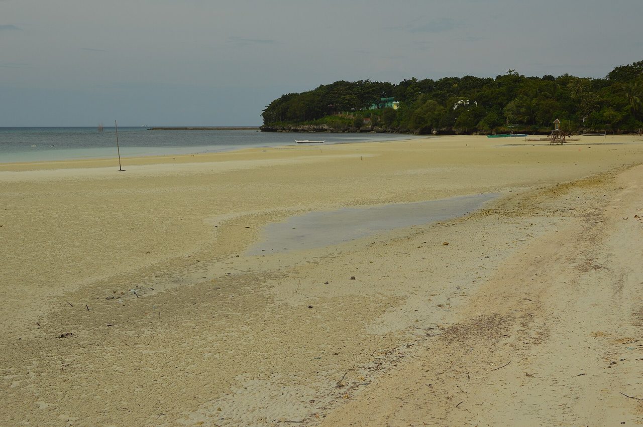 A near-empty palm-backed white-sand beach on Siquijor Island